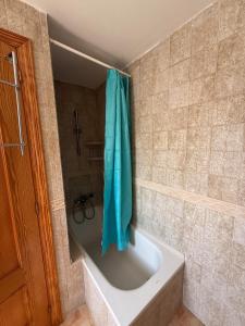 a bath tub with a blue shower curtain in a bathroom at Villa El Faro in Peñíscola