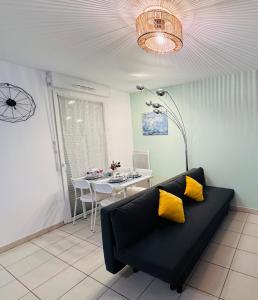 a living room with a black couch and a table at Proche Disney Paris Appartement cosy et familial pour 4 Pers-Wifi-Parking Privé in Bussy-Saint-Georges