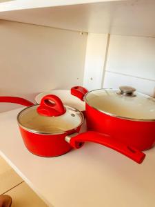 deux casseroles et poêles rouges posées sur un comptoir de cuisine dans l'établissement DF PLAZA - Lindo apartamento com suíte!, à Brasilia