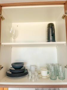 une armoire remplie d'assiettes, de bols et de tasses dans l'établissement DF PLAZA - Lindo apartamento com suíte!, à Brasilia