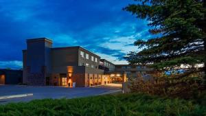 a large building with a tree in front of it at Days Inn by Wyndham Airdrie in Airdrie