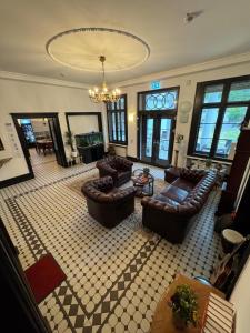 a large living room with leather furniture and a chandelier at Die Villa Hotel in Leverkusen