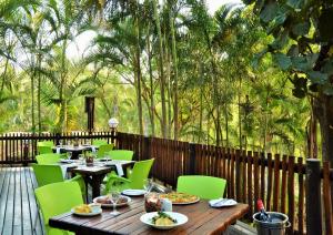 a wooden deck with tables and green chairs at eBundu Lodge in White River