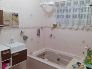 a white bathroom with a tub and a sink at Pé na areia in Ilha Comprida +22 photos