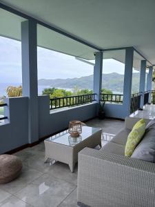 a balcony with couches and a table and some mountains at Royale Green Villa in Anse Royale