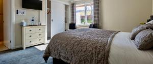 Un dormitorio con una cama y una cómoda con televisión. en Eldon Lea, en Strathpeffer