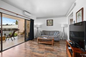 Una sala de estar con un sofá y un televisor. en Kona Plaza#414, en Kailua-Kona