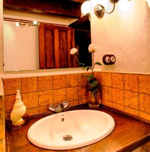 a sink in a bathroom with a mirror and flowers at Ruralmedulas Casa 2 in La Campañana