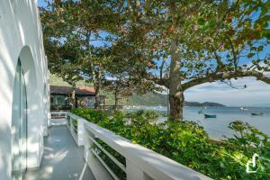 ein weißes Haus mit einem Baum und dem Wasser in der Unterkunft Beira-mar em Canto Grande para 08 pessoas in Canto Grande