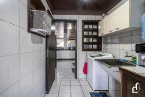 eine Küche mit einer Tür, die in eine Küche mit weißen Fliesen führt in der Unterkunft Beira-mar em Canto Grande para 08 pessoas in Canto Grande
