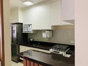 a kitchen with white cabinets and stainless steel appliances at Apartamento no Módulo 6 em Riviera de São Lourenço in Bertioga
