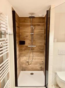 a shower in a bathroom with wooden walls at La Petite Maison in Villargondran