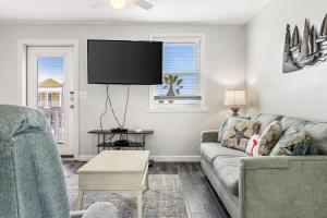 een woonkamer met een bank en een flatscreen-tv bij Breaking Even in Gulf Shores
