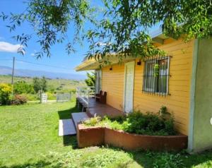 a small yellow house with a porch and a yard at Cabañas La Guadalupe in Villa Yacanto