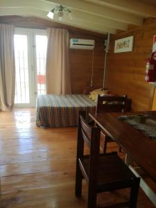 a living room with a table and a bed in a room at Cabañas La Guadalupe in Villa Yacanto
