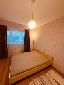 a bed in a room with a lamp and a window at Munamäe tänav 16-5 in Otepää