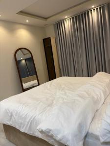 a bedroom with a large white bed and a mirror at شقة غرفه وصاله راقيه 2 العريض in Al Madinah