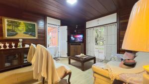 a living room with a couch and a tv at Casa de Praia a 150m da praia com Conforto Total Ar-Condicionado, Enxoval, Wi fi e Piscina Privativa in Peruíbe