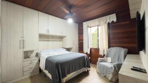 a bedroom with a bed and a chair and a window at Casa de Praia a 150m da praia com Conforto Total Ar-Condicionado, Enxoval, Wi fi e Piscina Privativa in Peruíbe +69 photos