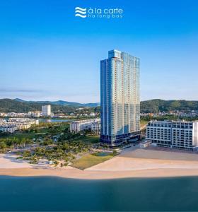 a tall building on the beach next to the ocean at Căn hộ 2PN view biển Alacarte Hạ Long, bể bơi vô cực in Ha Long
