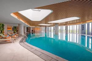 a swimming pool in a hotel lobby with windows at Căn hộ 2PN view biển Alacarte Hạ Long, bể bơi vô cực in Ha Long