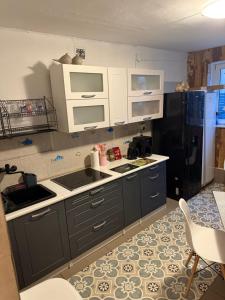 a kitchen with gray cabinets and a black refrigerator at Tififi przyczepa in Pobierowo