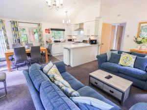 a living room with blue couches and a kitchen at Forest Pines Lodge in Bowness-on-Windermere