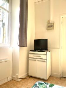 サン・ジュニアンにあるStudio meublé centre-ville Saint Junienのリビングルーム(白いキャビネットの上にテレビ付)