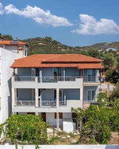 a white building with an orange tile roof at Blue Horizon Sarti Chalkidiki in Sarti