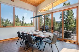 Un comedor con mesa y sillas y grandes ventanales. en Luxury Ski Chalet - 684 Vasquez Road, en Winter Park