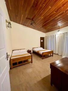 a room with two beds and a wooden ceiling at Semni Escape Plantation Bungalow-Vagamon in Vagamon