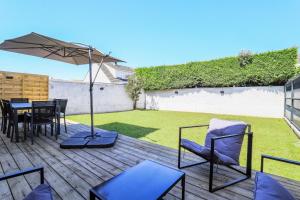a patio with a table and chairs and an umbrella at L'Orangerie, Maison moderne avec jardin in Berck-sur-Mer