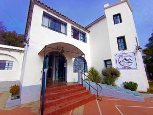 a white building with stairs leading to the front door at Hotel Paraiso in La Cumbre