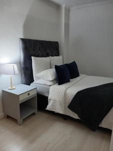 1 dormitorio con 1 cama y mesa auxiliar con lámpara en 2 Bedroom Apartment in Cape Town, en Vosburg
