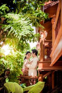 a man and woman standing on a balcony of a house at Ruen Tai Boutique in Nai Yang Beach