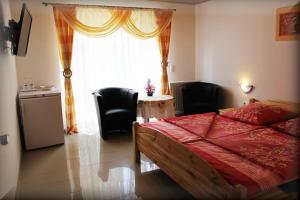 Un dormitorio con una cama y sillas y una ventana. en Pension Cecilia, en Norddeich