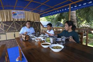 a group of people sitting at a table eating food at Riveria Caravan Houseboat in Champakulam