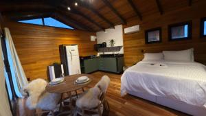 a bedroom with a bed and a table with two chairs at Vila Chamonix - Chalé Cabernet in Urubici