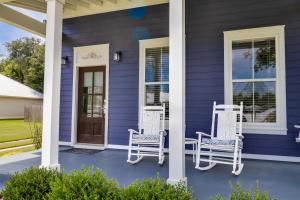ein blaues Haus mit weißen Stühlen auf der Veranda in der Unterkunft Cottage at Bella Vista in Foley