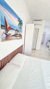 a white bed in a room with a painting on the wall at Conforto a 200 m da Praia de Atalaia com ar in Atalaia Velha