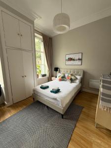 1 dormitorio con 1 cama blanca grande con alfombra en Charming studio flat in vibrant Leith, en Edimburgo