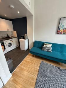 Una sala de estar con un sofá azul y una cocina. en Charming studio flat in vibrant Leith, en Edimburgo