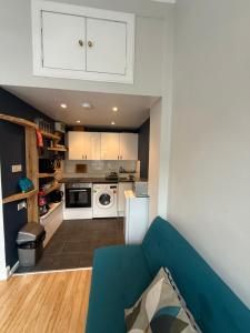 cocina con sofá azul en una habitación en Charming studio flat in vibrant Leith, en Edimburgo 3 fotos más