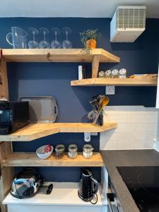 Una cocina con estantes de madera en una pared azul. en Charming studio flat in vibrant Leith, en Edimburgo
