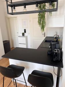a kitchen with a black counter and two chairs at Modernes Apartment Karlsruhe in Karlsruhe +1 photo