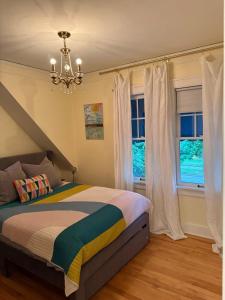 a bedroom with a bed with a chandelier and windows at 3 bedroom home next to downtown and medical mile in Grand Rapids