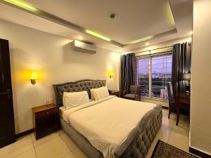 a bedroom with a bed and a desk and a window at The Grandview Manor - 2 Bed Luxury Apartment with City Views in Rawalpindi