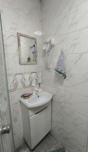 un bagno bianco con lavandino e specchio di Комфортный дом до 4х человек. Есть парковка на 2 машины, Wi-Fi, TV. a Bishkek