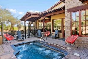 a swimming pool with red chairs and a house at Tranquility at The Rocks Club/Troon in Scottsdale