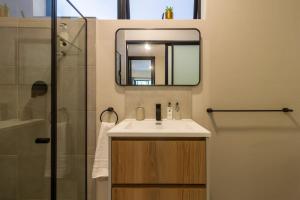a bathroom with a sink and a mirror and a shower at #AlimamaSpaces The Rob's Akaru in Johannesburg +29 photos